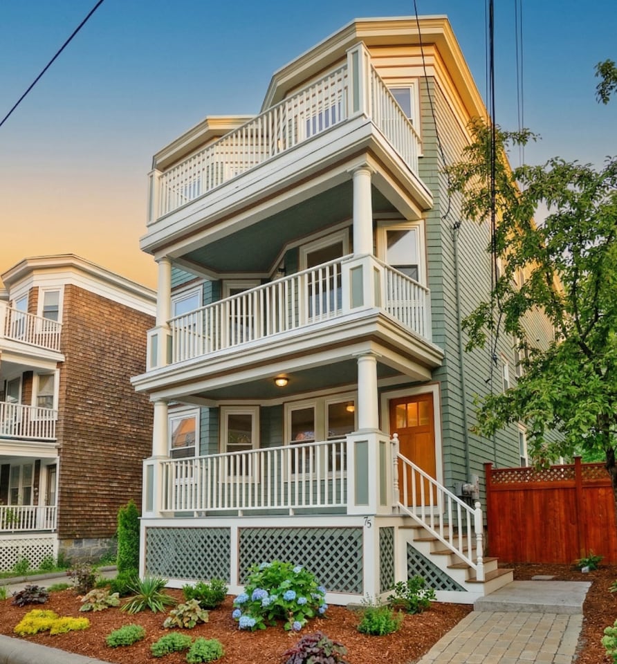 Three-story residential building at 17 Smith Place with green siding, white trim, and multiple balconies, surrounded by landscaping and a paved driveway.